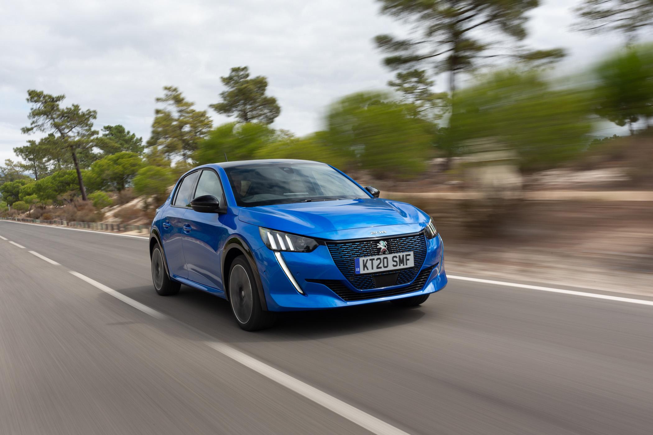 a dark blue peugeot e-208 driving on a road