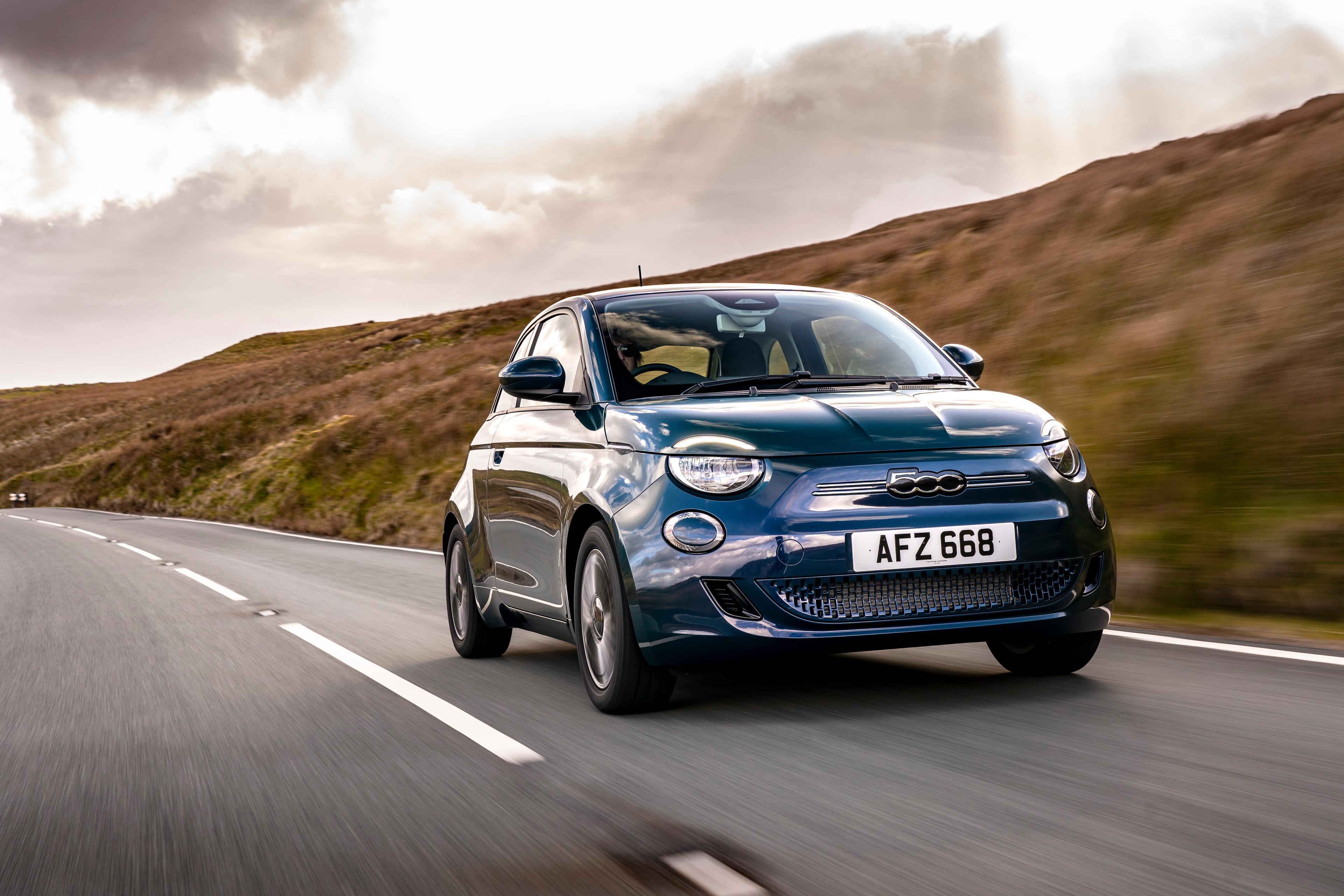 Fiat 500e dark blue driving in the countryside