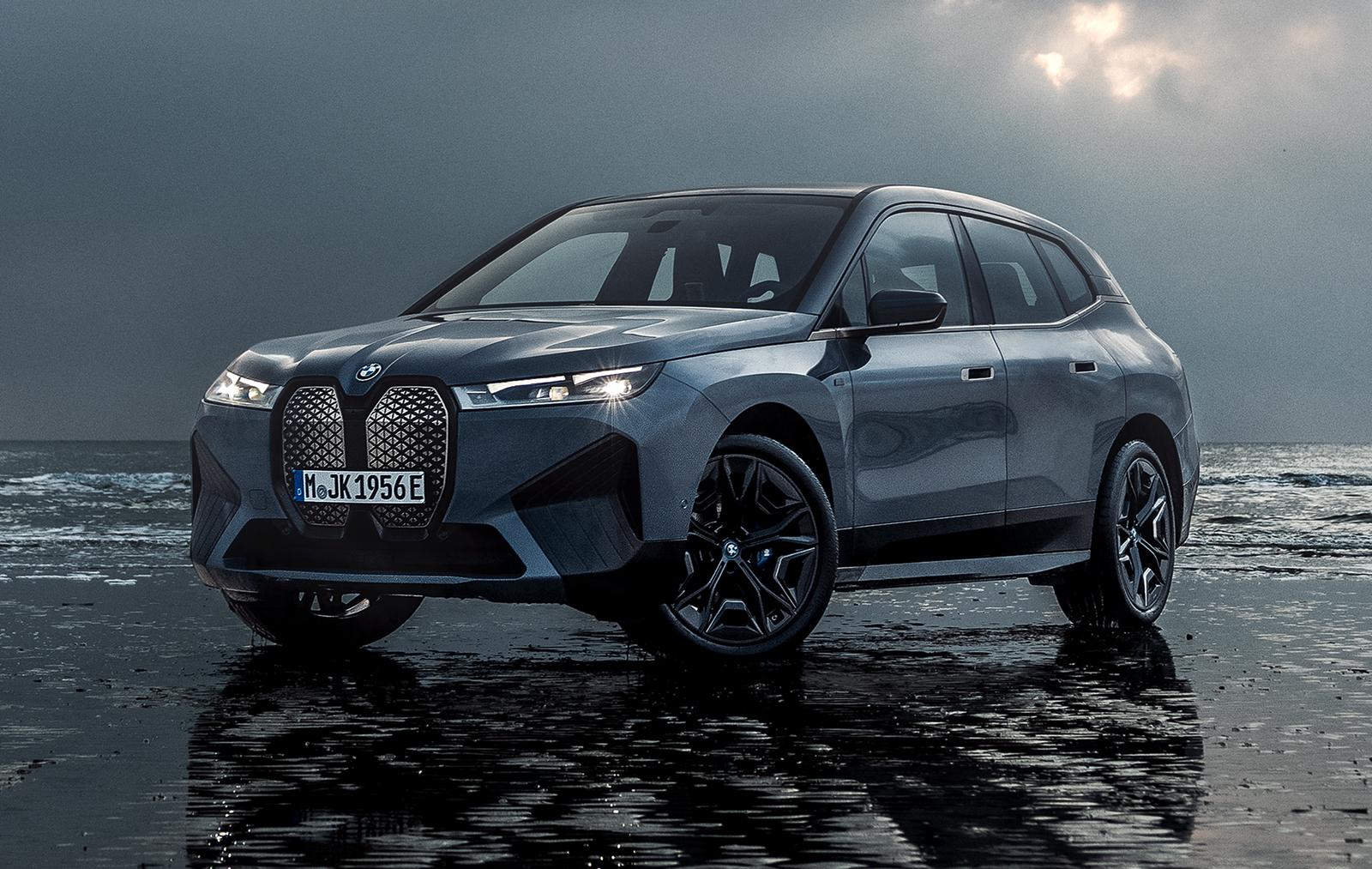 a black/grey bmw ix parked by the sea at night